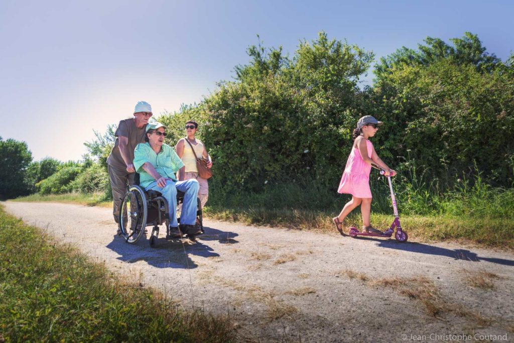 un groupe de personnes, dont une en fauteuil roulant, se baladent sur un sentier au bord de l'étang du Louroux
