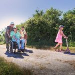 un groupe de personnes, dont une en fauteuil roulant, se baladent sur un sentier au bord de l'étang du Louroux