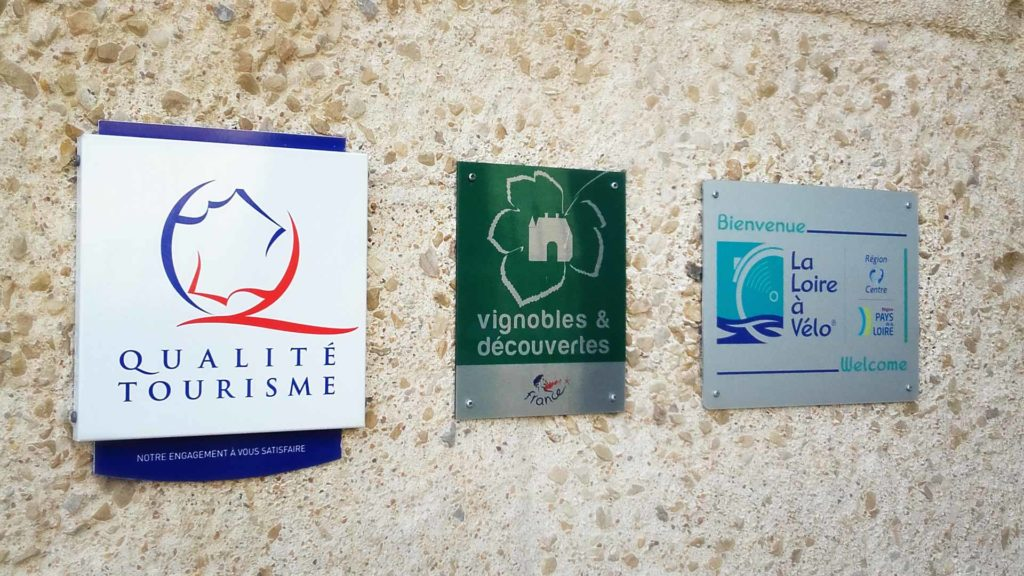 Des pannonceaux Qualité Tourisme, Vignobles et découvertes et la Loire à Vélo accrochés sur un mur