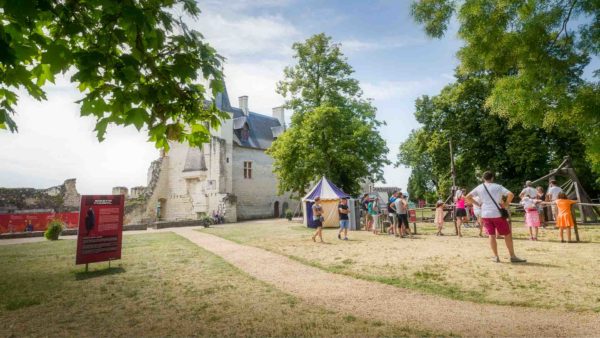 Des visiteurs se baladent dans la cour de la forteresse de Chinon occupée par une tente médiévale