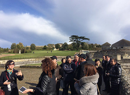 Un guide mène un groupe de visiteurs dan sla cour d'un château