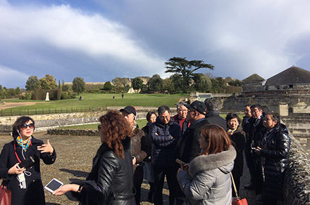 Un guide mène un groupe de visiteurs dan sla cour d'un château