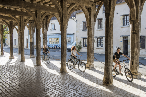 Un groupe de trois cyclistes circulent sous les halles médiévales de Montrésor